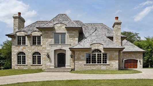 A large stone house with a brick walkway.