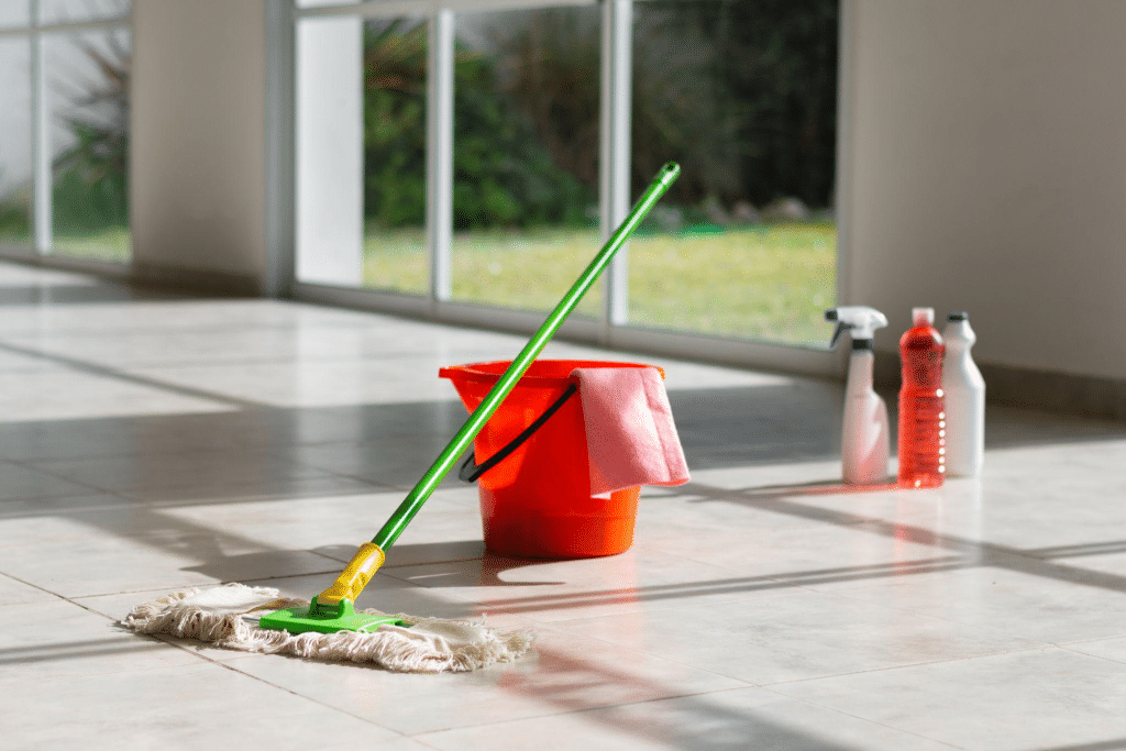 A cleaning mop and bucket on a tile floor.