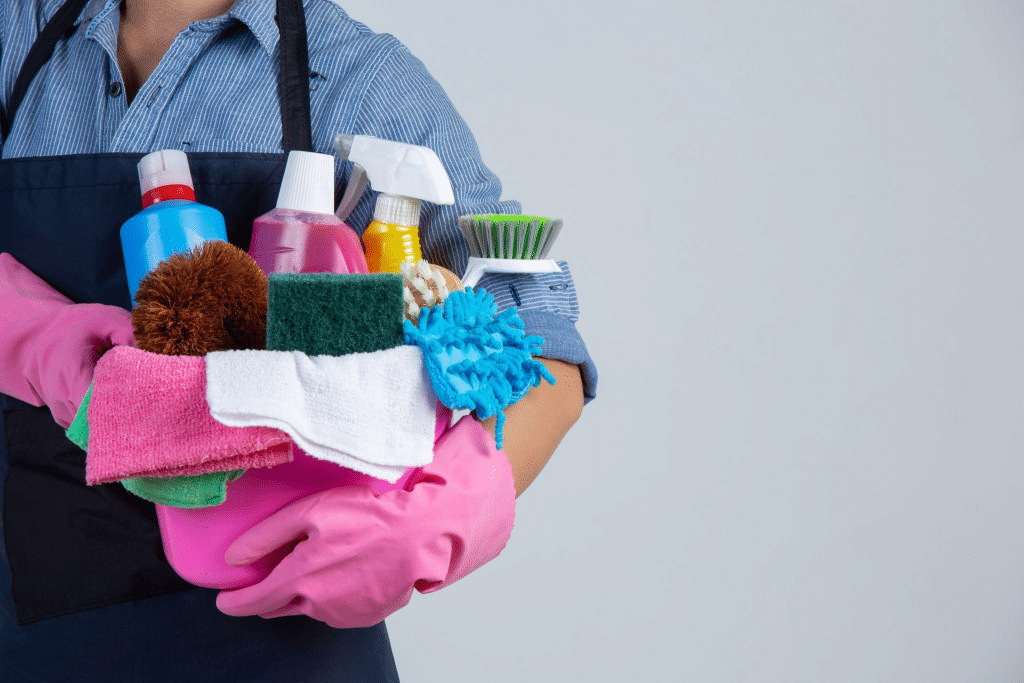 Person holding a basin filled with various floor cleaning supplies