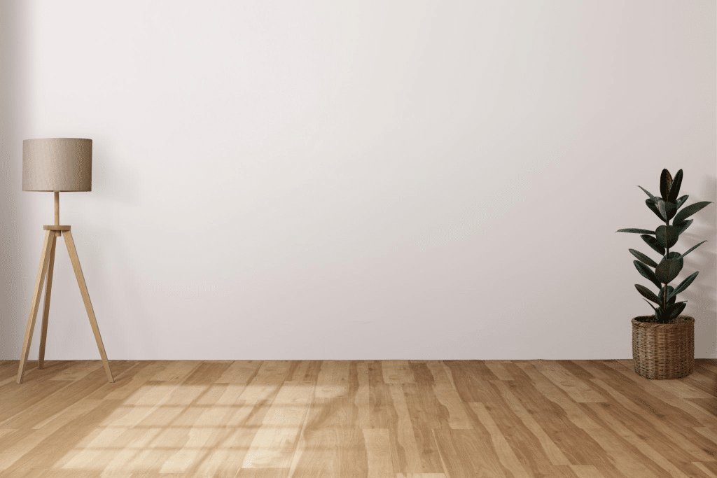Hardwood floor in a room with a standing lamp and white walls